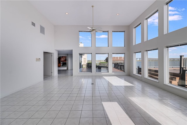 unfurnished living room featuring a high ceiling, light tile patterned floors, and ceiling fan