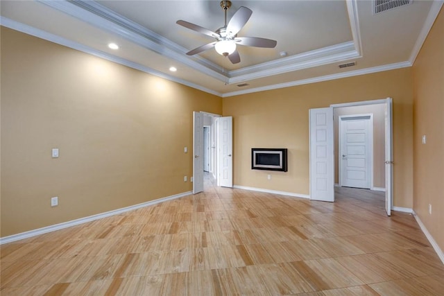 spare room featuring baseboards, visible vents, a raised ceiling, and crown molding