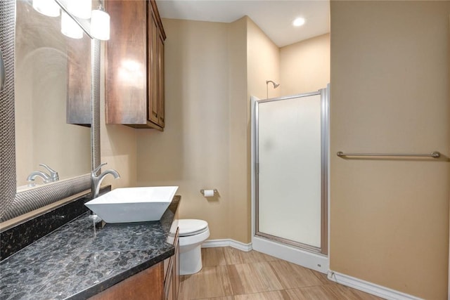 full bath featuring a stall shower, vanity, toilet, and baseboards