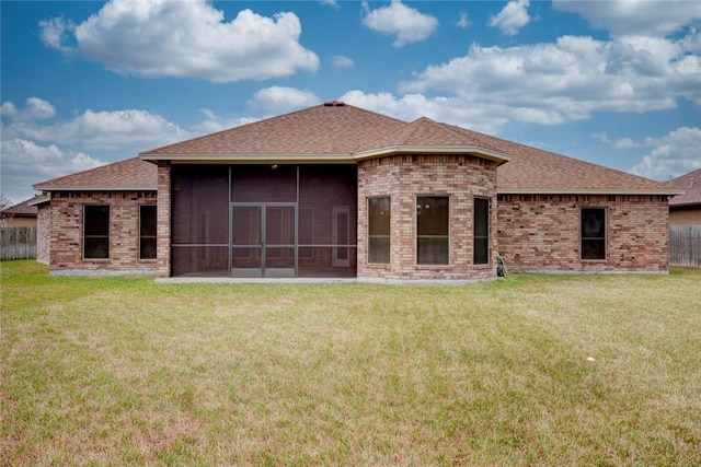 back of house featuring a sunroom, brick siding, a lawn, and fence