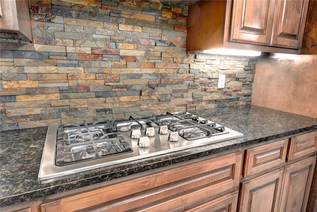 kitchen with stainless steel gas cooktop, dark stone countertops, and decorative backsplash