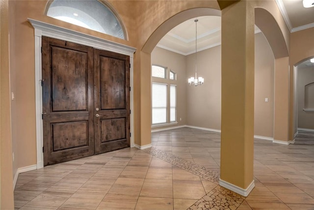 entryway featuring light tile patterned floors, baseboards, arched walkways, ornamental molding, and a notable chandelier