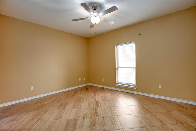 empty room with ceiling fan and baseboards