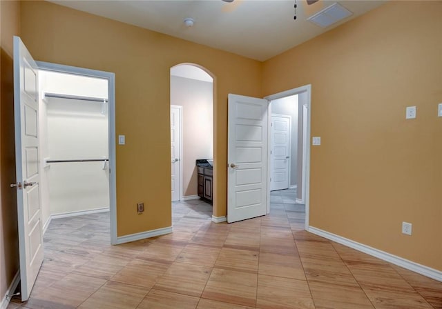 spare room featuring a ceiling fan, arched walkways, visible vents, and baseboards