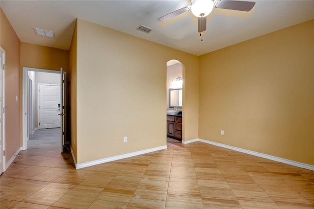 spare room with arched walkways, visible vents, and baseboards