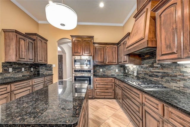 kitchen with custom range hood, appliances with stainless steel finishes, arched walkways, and crown molding