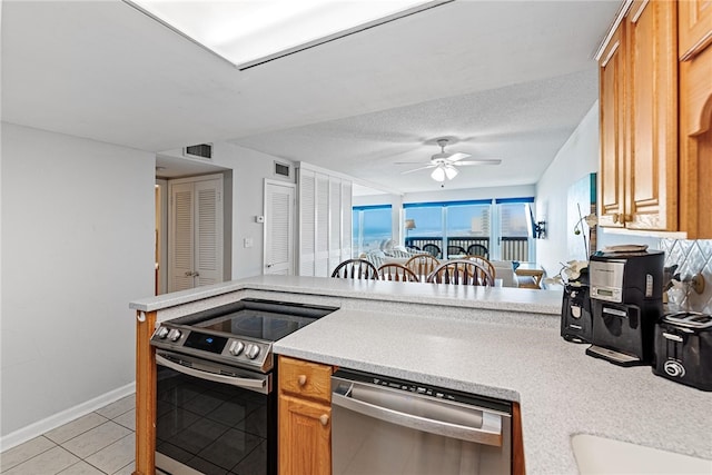 kitchen with appliances with stainless steel finishes, a textured ceiling, light tile patterned floors, kitchen peninsula, and ceiling fan