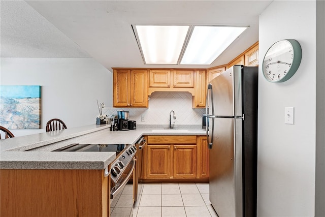 kitchen with light tile patterned flooring, sink, kitchen peninsula, appliances with stainless steel finishes, and decorative backsplash