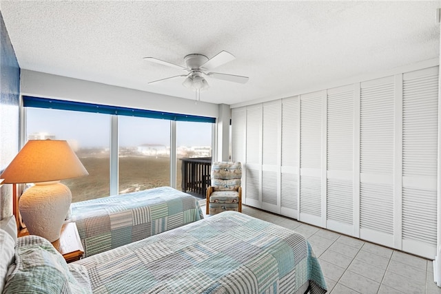 tiled bedroom featuring a textured ceiling, ceiling fan, and a closet