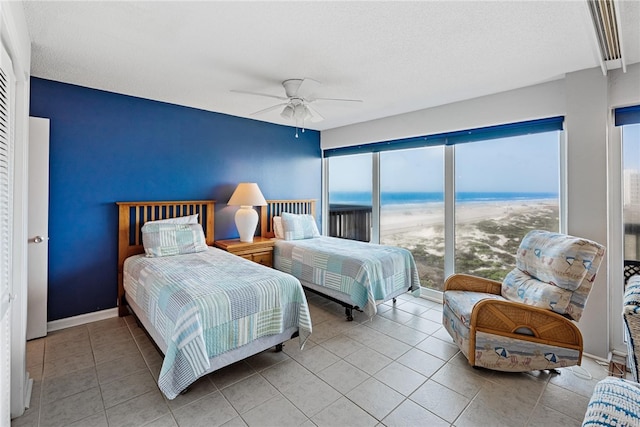 bedroom with light tile patterned flooring, ceiling fan, multiple windows, and a water view