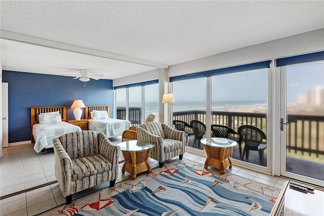 tiled bedroom with access to exterior, a textured ceiling, a water view, and multiple windows