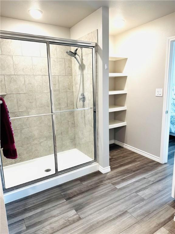 1353 Regents Park Ln, Corpus Christi, TX 78415 - bathroom with a stall shower, wood finished floors, and baseboards