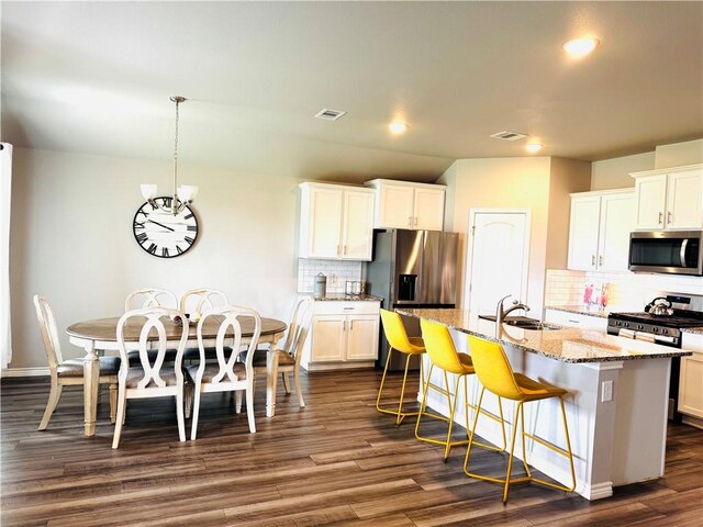 1353 Regents Park Ln, Corpus Christi, TX 78415 - kitchen featuring stainless steel appliances, a sink, decorative backsplash, dark wood finished floors, and an island with sink