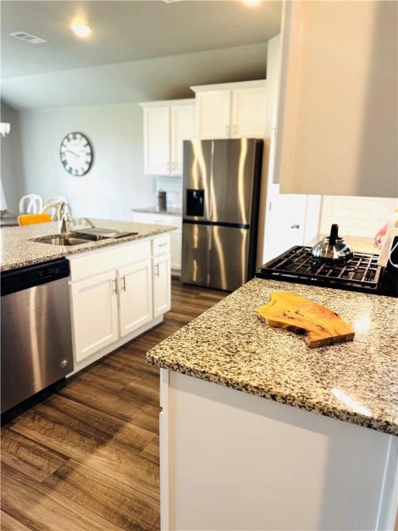 1353 Regents Park Ln, Corpus Christi, TX 78415 - kitchen featuring appliances with stainless steel finishes, dark wood-style flooring, a sink, light stone countertops, and white cabinetry