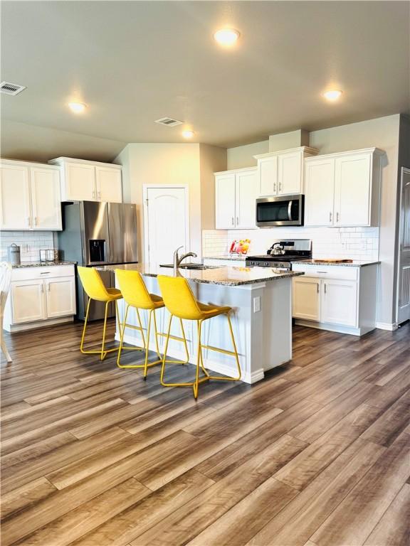1353 Regents Park Ln, Corpus Christi, TX 78415 - kitchen with appliances with stainless steel finishes, backsplash, dark wood-style floors, white cabinetry, and recessed lighting