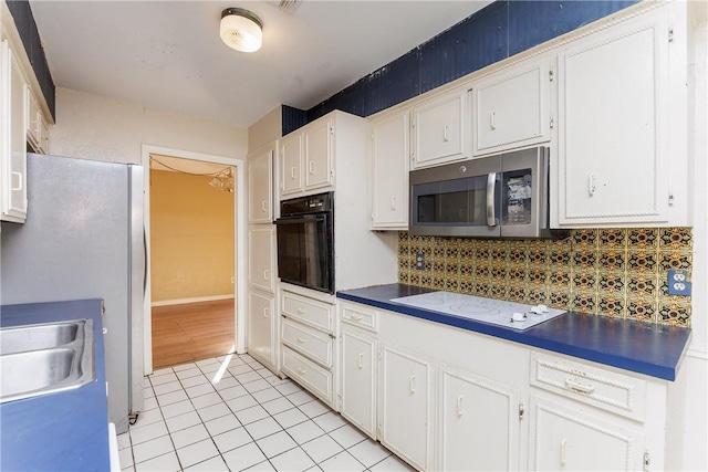 kitchen with light tile patterned flooring, sink, stainless steel appliances, decorative backsplash, and white cabinets