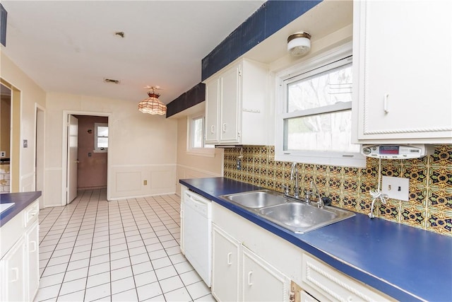 kitchen with light tile patterned flooring, tasteful backsplash, white cabinetry, dishwasher, and sink