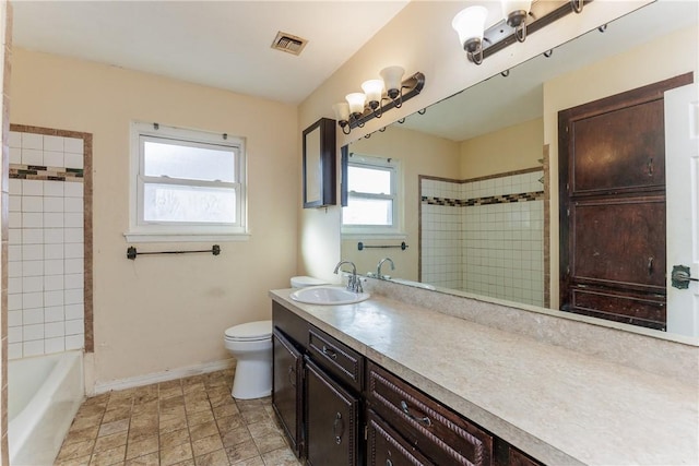 full bathroom with vanity, tiled shower / bath, and toilet