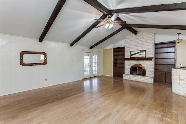 unfurnished living room with french doors, lofted ceiling with beams, light hardwood / wood-style flooring, ceiling fan, and a fireplace