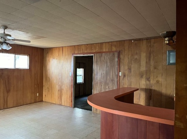 interior space with ceiling fan and wooden walls