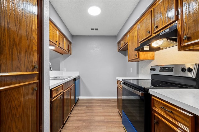 kitchen featuring sink, light hardwood / wood-style floors, a textured ceiling, and appliances with stainless steel finishes