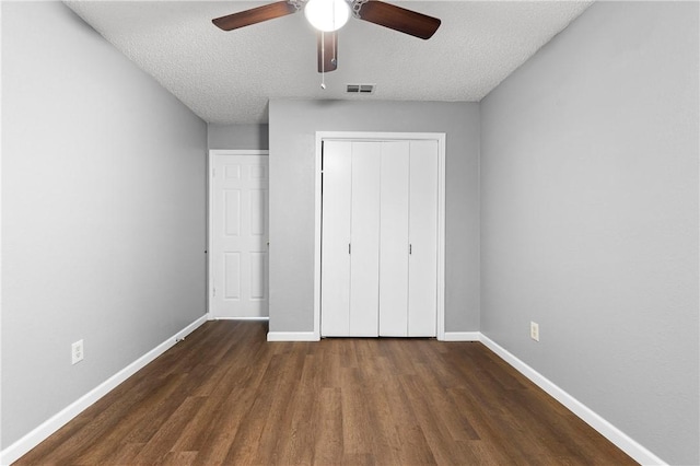 unfurnished bedroom featuring a textured ceiling, ceiling fan, a closet, and dark hardwood / wood-style floors