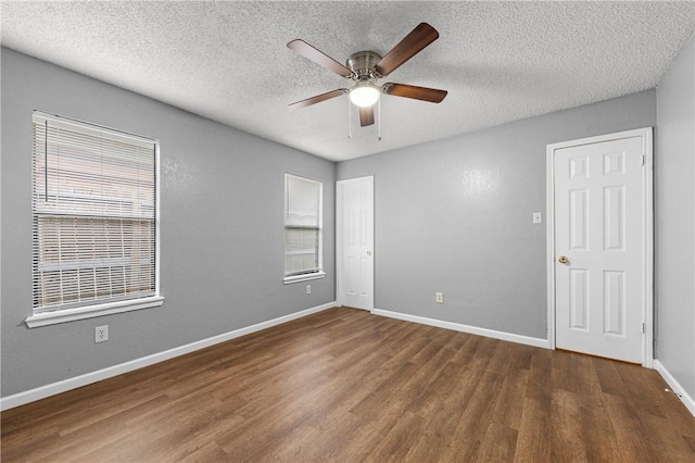 spare room with a textured ceiling, a healthy amount of sunlight, and dark hardwood / wood-style floors