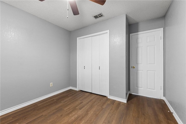 unfurnished bedroom with ceiling fan, dark hardwood / wood-style floors, a textured ceiling, and a closet