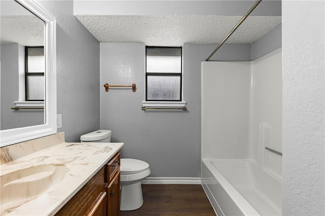 full bathroom with vanity, bathtub / shower combination, hardwood / wood-style flooring, toilet, and a textured ceiling