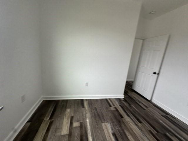 unfurnished bedroom featuring dark wood-style floors and baseboards