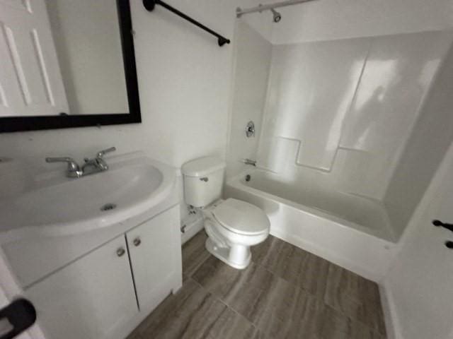 bathroom with  shower combination, wood finished floors, vanity, and toilet