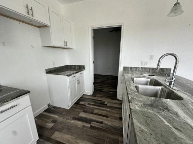 kitchen featuring dark wood-style floors, dark stone counters, white cabinetry, and a sink