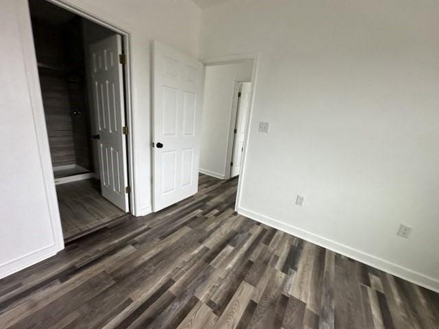 empty room featuring dark wood-style floors and baseboards