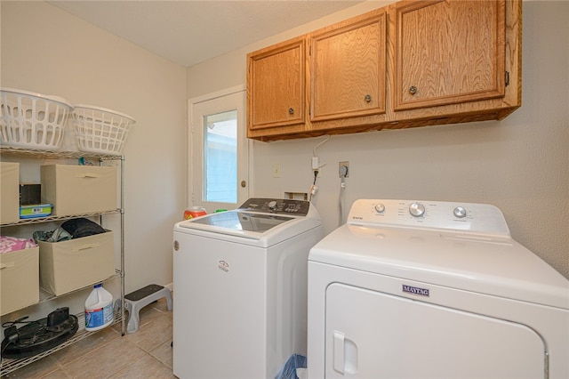 clothes washing area featuring cabinets, washer and clothes dryer, and light tile patterned flooring