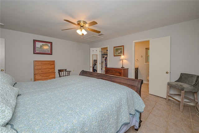 bedroom with light tile patterned flooring, ceiling fan, ensuite bath, and a walk in closet