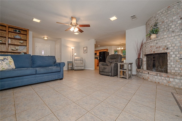 tiled living room featuring a fireplace and ceiling fan with notable chandelier