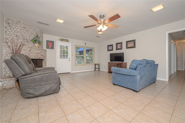 living room featuring a fireplace, ceiling fan, and light tile patterned floors