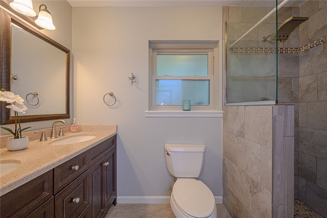 bathroom featuring toilet, vanity, tile patterned flooring, and a tile shower