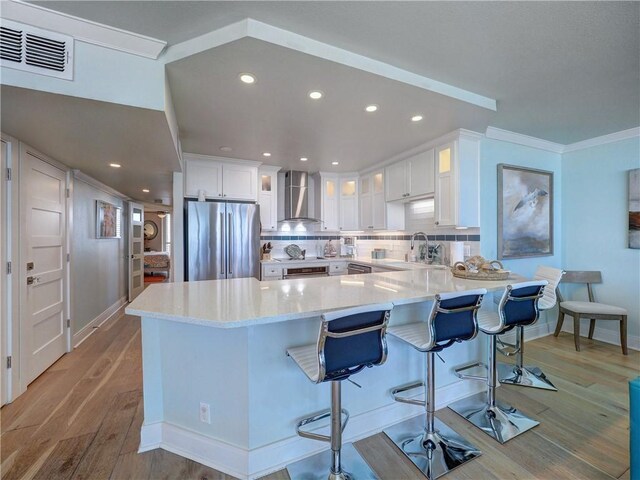 6649 Seacomber Dr Unit 1007, Port Aransas, TX 78373 - kitchen featuring freestanding refrigerator, wall chimney exhaust hood, a peninsula, light wood-style flooring, and a sink