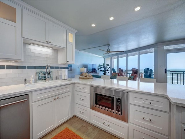 6649 Seacomber Dr Unit 1007, Port Aransas, TX 78373 - kitchen featuring a sink, appliances with stainless steel finishes, white cabinetry, light wood-style flooring, and backsplash