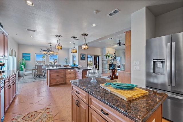 kitchen featuring stainless steel refrigerator with ice dispenser, ceiling fan, light tile patterned floors, decorative light fixtures, and a kitchen island