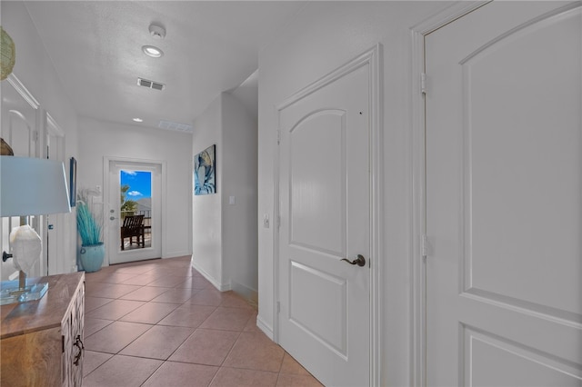 hallway with light tile patterned flooring and a textured ceiling