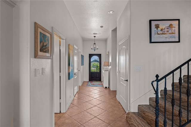 interior space with a textured ceiling, a notable chandelier, and light tile patterned flooring