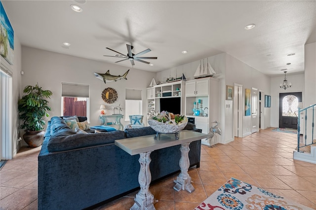 tiled living room featuring ceiling fan with notable chandelier and plenty of natural light