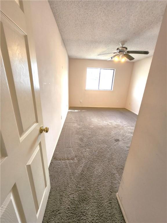 unfurnished room with a textured ceiling, carpet floors, and ceiling fan