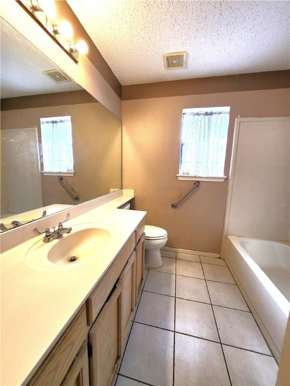 bathroom with a wealth of natural light, tile patterned flooring, vanity, and a textured ceiling