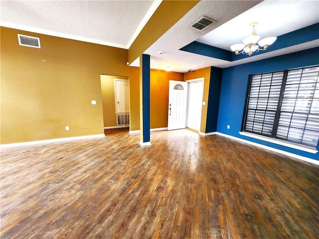 unfurnished room featuring a tray ceiling, hardwood / wood-style flooring, a textured ceiling, and an inviting chandelier