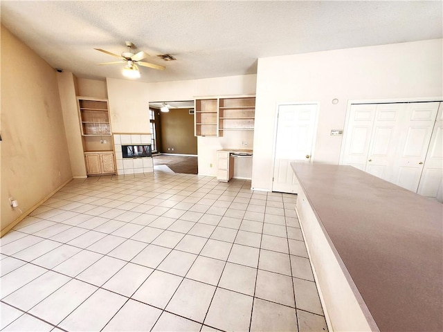 unfurnished living room with a textured ceiling, ceiling fan, and light tile patterned flooring