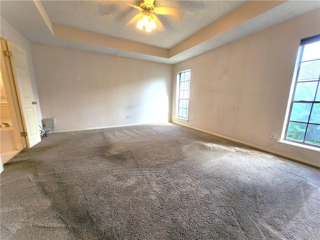 carpeted spare room with a tray ceiling and ceiling fan