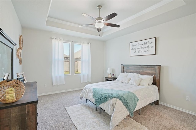 carpeted bedroom with ceiling fan and a tray ceiling